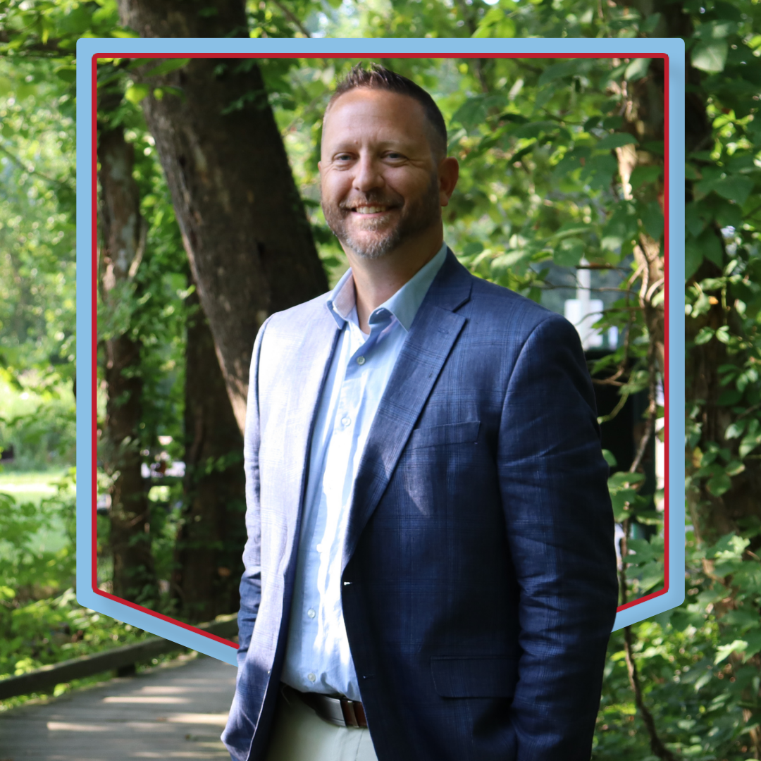 Jason Schackow poses in front of a wooded background.
